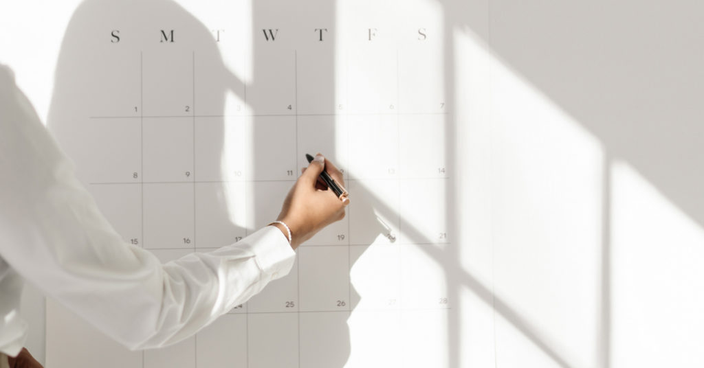 Eine Frau notiert ihre Pläne an einem Kalender an der Wand